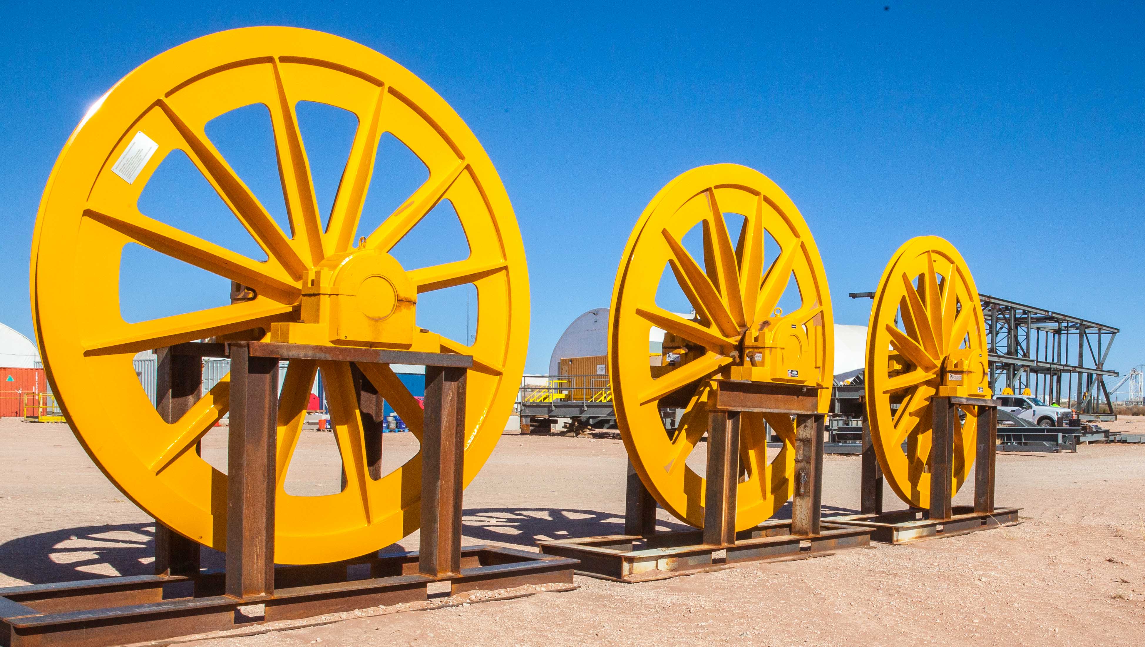 Bullwheels await installation atop the headframe, which is currently being assembled. Cables will run over these pulleys and connect to the top of the Galloway